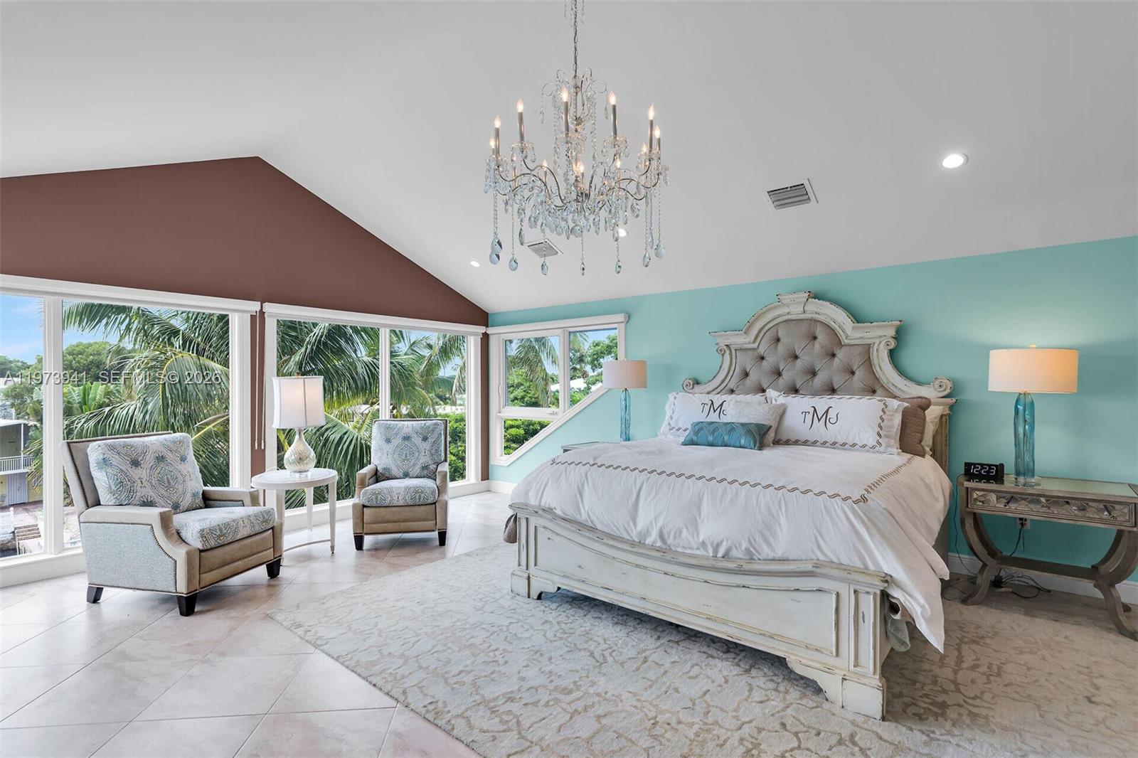 A bedroom features a vaulted ceiling, a crystal chandelier, and large windows overlooking palm trees — 1218 Mockingbird Rd, Key Largo FL 33037, KEY LARGO, FL