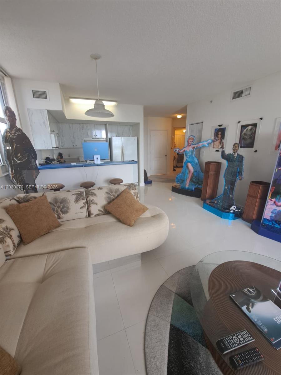 A living room features a beige sectional sofa, white tile floors, and several life-sized celebrity cutouts — 5085 NW 7th St # 602, Miami FL 33126, MIAMI, FL