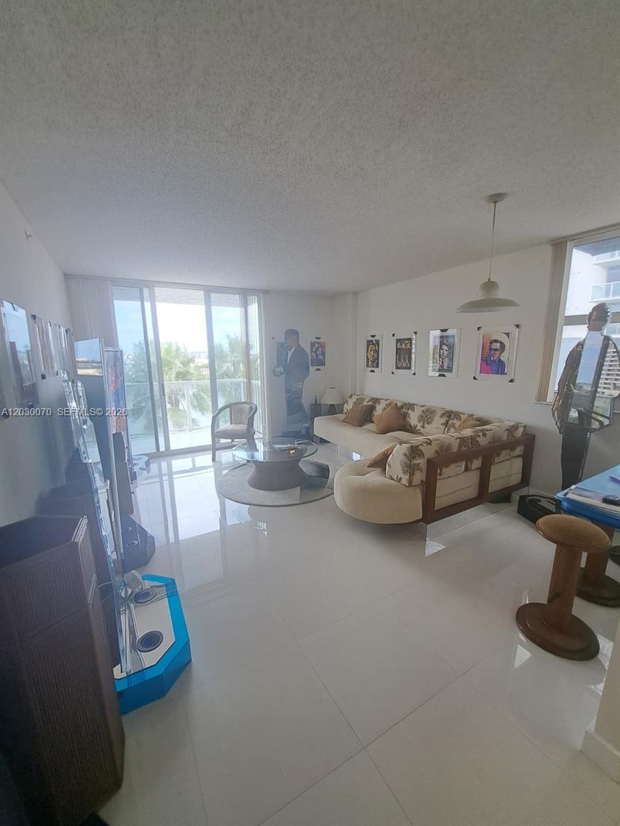 A living room features white tile floors, a patterned sofa, and a balcony view — 5085 NW 7th St # 602, Miami FL 33126, MIAMI, FL