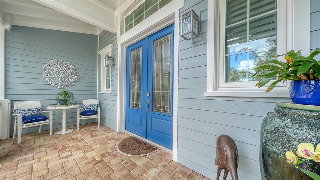 A covered porch features light blue siding, a blue double door, and brick paver flooring — 1794 CUNLIFF LANE, SARASOTA, FL