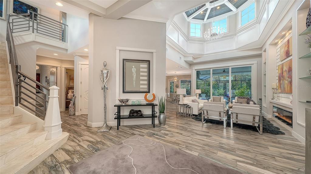 A spacious living room features a grand staircase, tile flooring, and a high vaulted ceiling — 1794 CUNLIFF LANE, SARASOTA, FL
