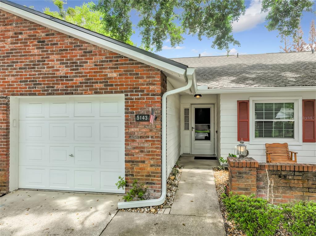 A brick and white siding house exterior features a garage, front door, and small porch — 5143 LAZY OAKS DRIVE UNIT 5143, WINTER PARK, FL