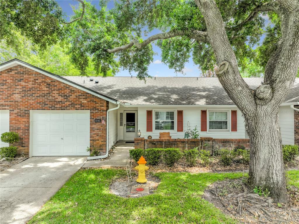 A single-story brick and white siding house with a garage, front patio, and fire hydrant — 5143 LAZY OAKS DRIVE UNIT 5143, WINTER PARK, FL