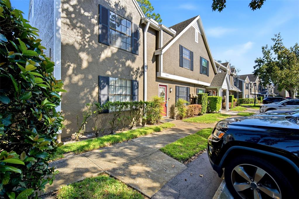 A two-story townhouse exterior with brown stucco walls, dark shutters, and a red front door — 16545 LAKE BRIGADOON CIRCLE, TAMPA, FL