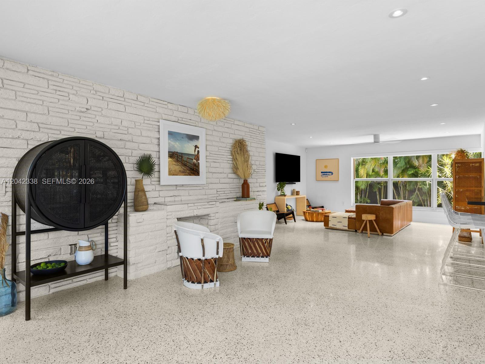 A spacious living room features a white brick wall, terrazzo floors, and modern furniture — 1000 NE 85th St, Miami FL 33138, MIAMI, FL