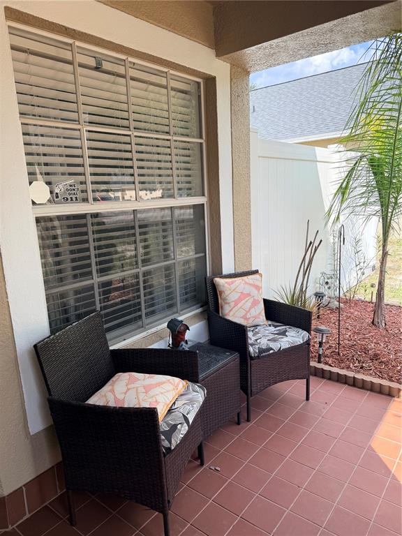 A covered patio features two wicker chairs with patterned cushions and a small side table — 218 RONALDALE AVENUE, HAINES CITY, FL