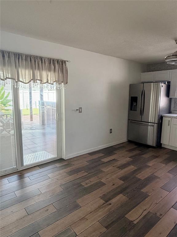 A dining area with wood-look tile flooring, a sliding glass door, and a stainless refrigerator — 218 RONALDALE AVENUE, HAINES CITY, FL