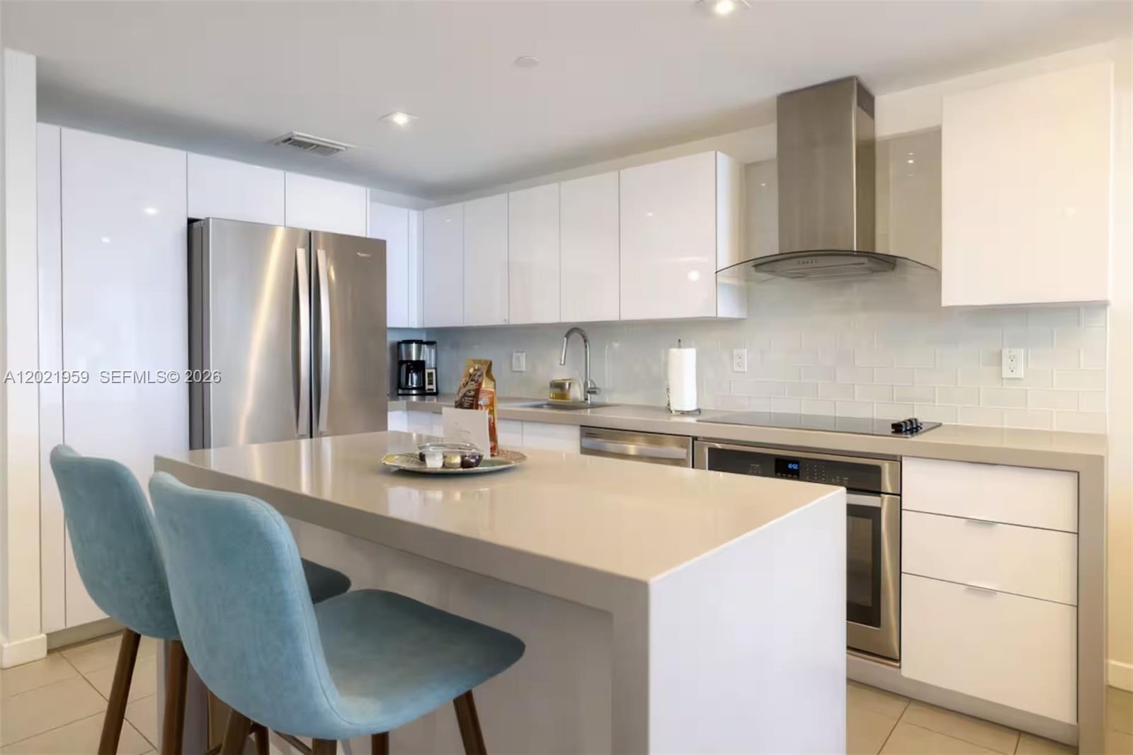A modern kitchen features white cabinets, stainless steel appliances, and a central island with chairs — 1600 NE 1st Ave # 1605, Miami FL 33132, MIAMI, FL