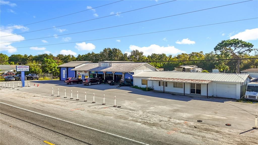 An exterior view of a commercial automotive repair shop with a large paved parking lot — 16924 SHADY HILLS ROAD, SPRING HILL, FL