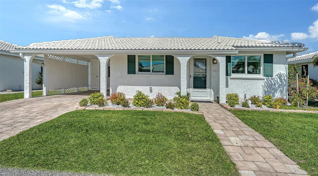 A single-story white house features a tiled roof, a carport, and a front walkway — 909 SPANISH DRIVE N, LONGBOAT KEY, FL