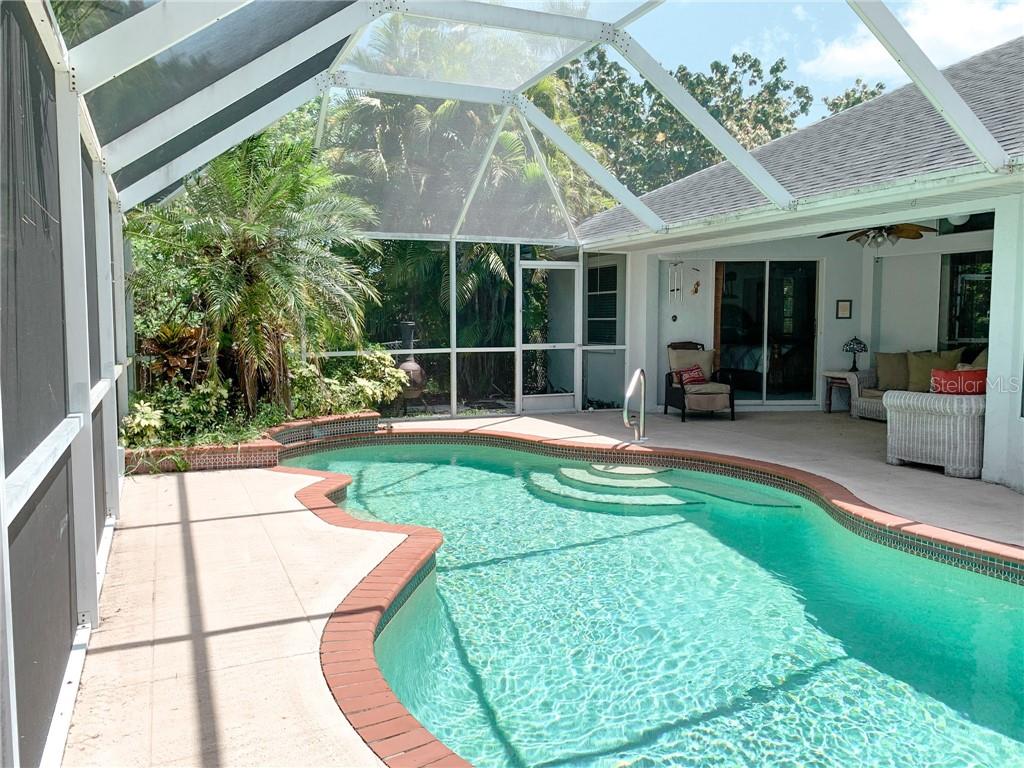 A screened-in patio features a swimming pool with brick coping and surrounding lounge furniture — 1000 CHEVY CHASE STREET, PORT CHARLOTTE, FL