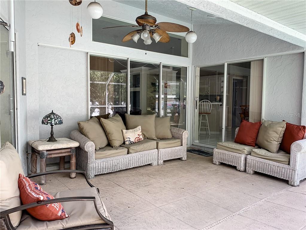 A covered patio features wicker furniture, a ceiling fan, and sliding glass doors — 1000 CHEVY CHASE STREET, PORT CHARLOTTE, FL