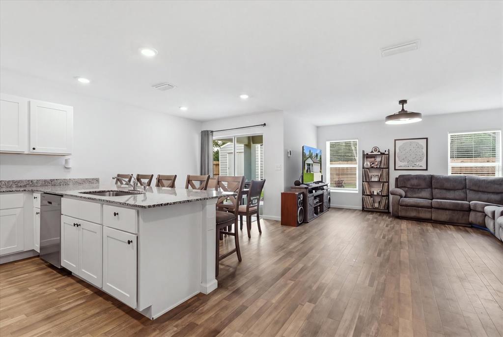 An open-concept kitchen and living area featuring white cabinets, a granite island, and wood flooring — 8830 N SPARTAN DRIVE, CITRUS SPRINGS, FL