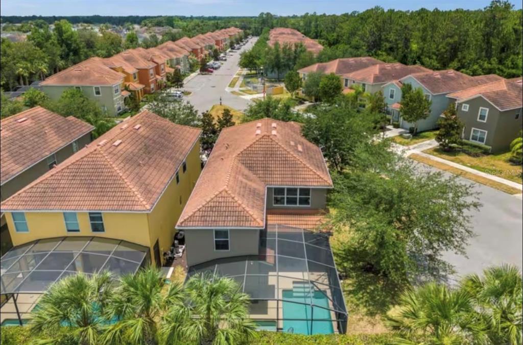 An aerial view shows two-story houses with tile roofs, screened-in pools, and a neighborhood street — 2989 BANANA PALM DRIVE, KISSIMMEE, FL