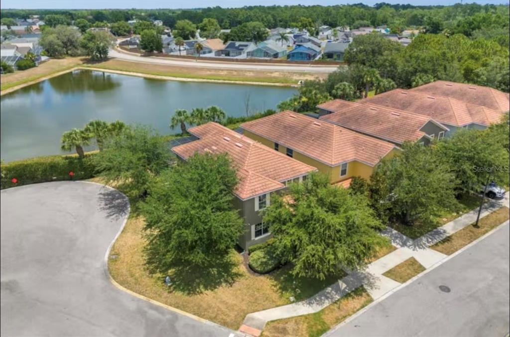 An aerial view shows a multi-unit residential building with a tile roof near a pond — 2989 BANANA PALM DRIVE, KISSIMMEE, FL