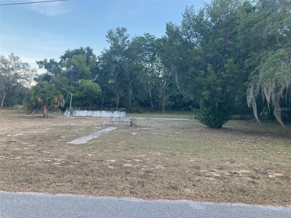 A vacant lot features a concrete walkway, small steps, and a low wall near trees — 2830 LAUREL AVENUE, LAKE WALES, FL