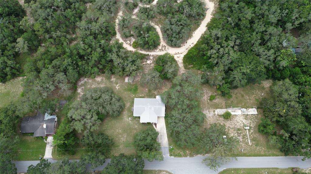 An aerial view shows a house with a driveway surrounded by trees and a dirt path — 2830 LAUREL AVENUE, LAKE WALES, FL
