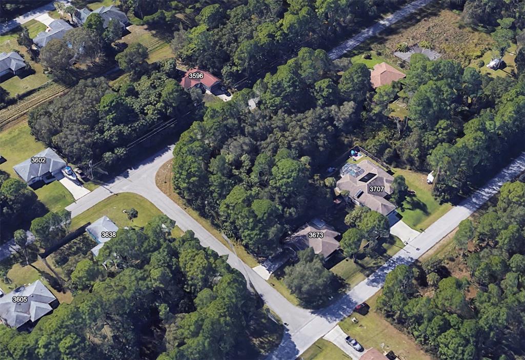 An aerial view shows several houses surrounded by dense trees and paved residential streets — Lot 13 GIBLIN DRIVE, NORTH PORT, FL