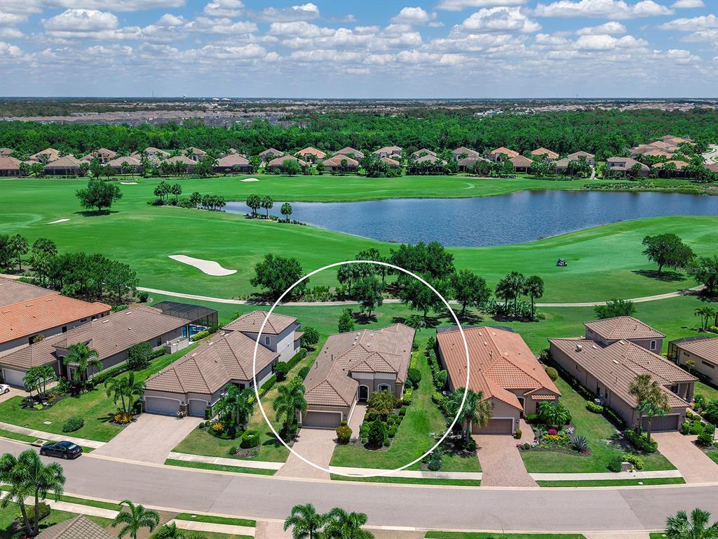 An aerial view shows a residential house with a tiled roof in a golf course community — 5137 NAPOLI RUN, BRADENTON, FL