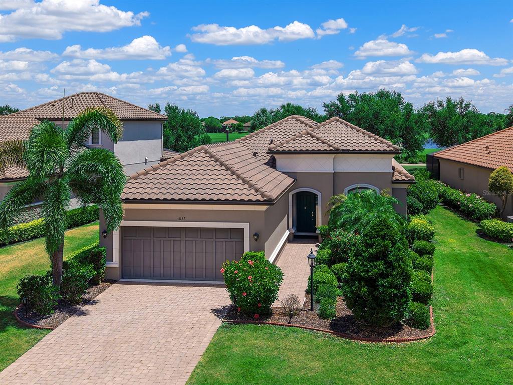 An aerial view of a single-story house with a tile roof and a paved driveway — 5137 NAPOLI RUN, BRADENTON, FL