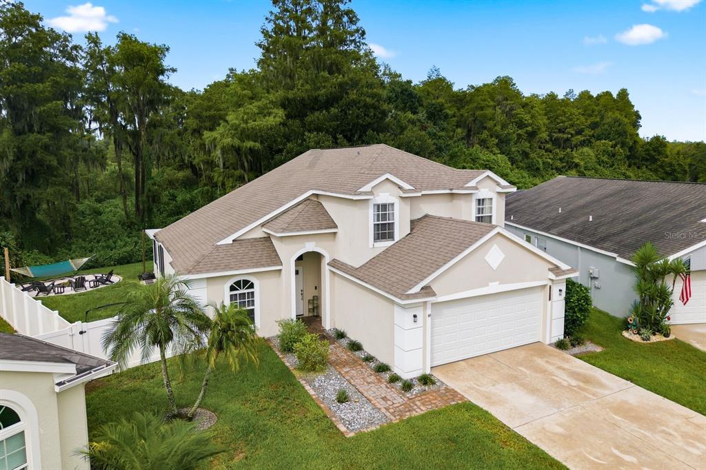 An elevated exterior view of a two-story beige house with a two-car garage and lawn — 4730 WOLFRAM LANE, NEW PORT RICHEY, FL