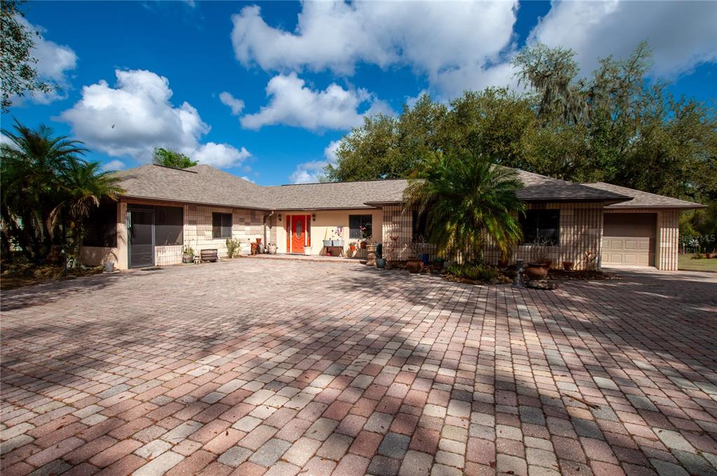 A single-story house with a brick-paved driveway and a bright orange front door — 2827 SE CREEKWOOD TERRACE, ARCADIA, FL