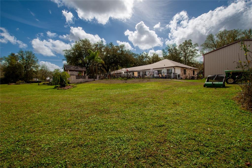 A large grassy backyard features a single-story house, a detached garage, and mature trees — 2827 SE CREEKWOOD TERRACE, ARCADIA, FL
