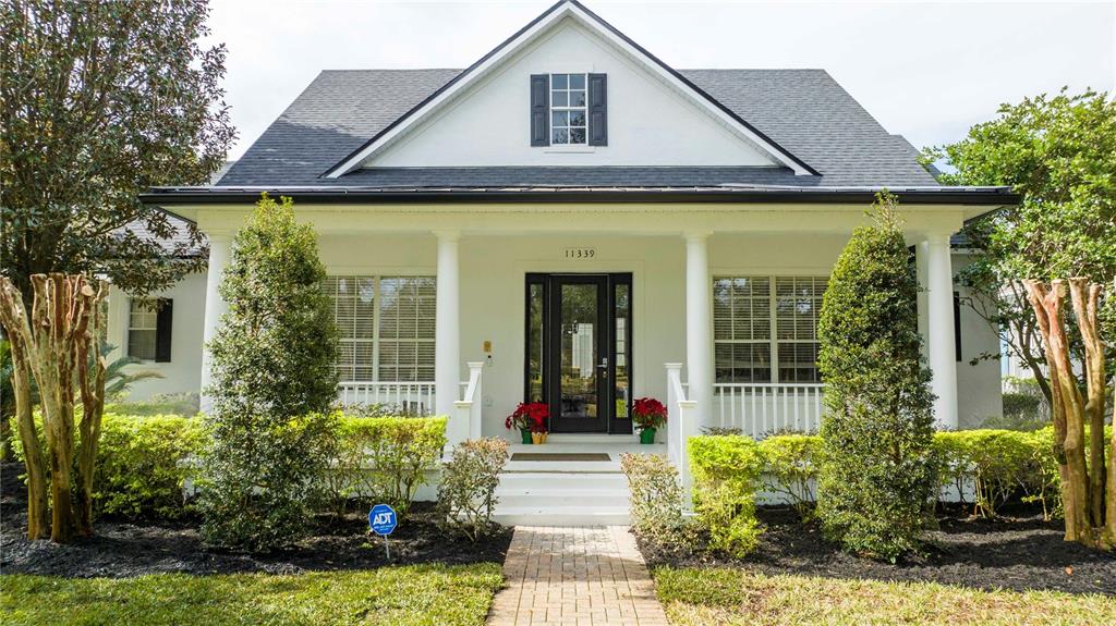 A white house with a front porch, columns, and a brick walkway — 11339 CAMDEN PARK DRIVE, WINDERMERE, FL