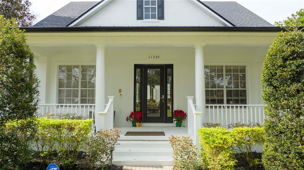 A white house exterior features a front porch with columns and a black front door — 11339 CAMDEN PARK DRIVE, WINDERMERE, FL