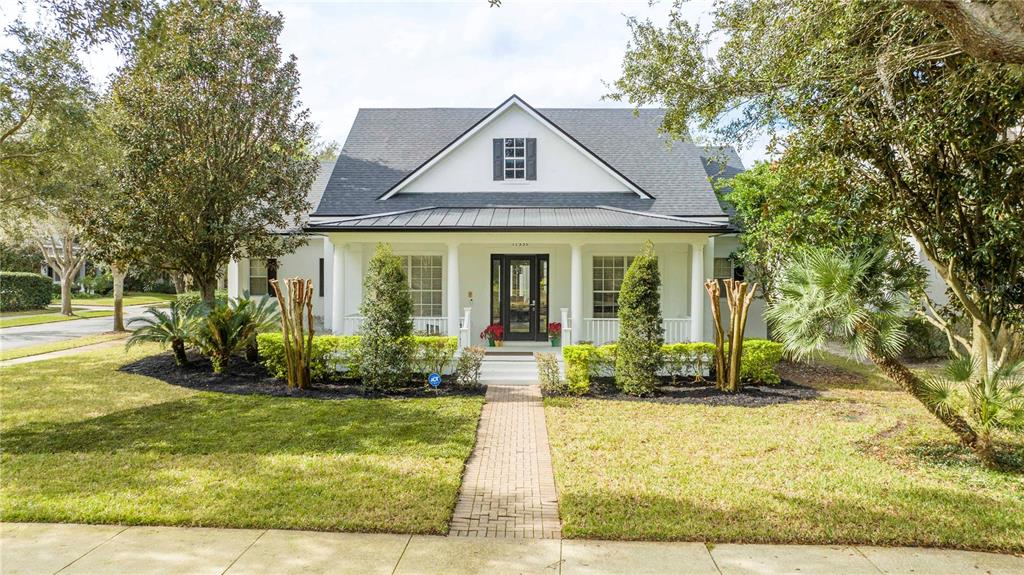 A white house with a dark roof and a front porch sits behind a lawn — 11339 CAMDEN PARK DRIVE, WINDERMERE, FL