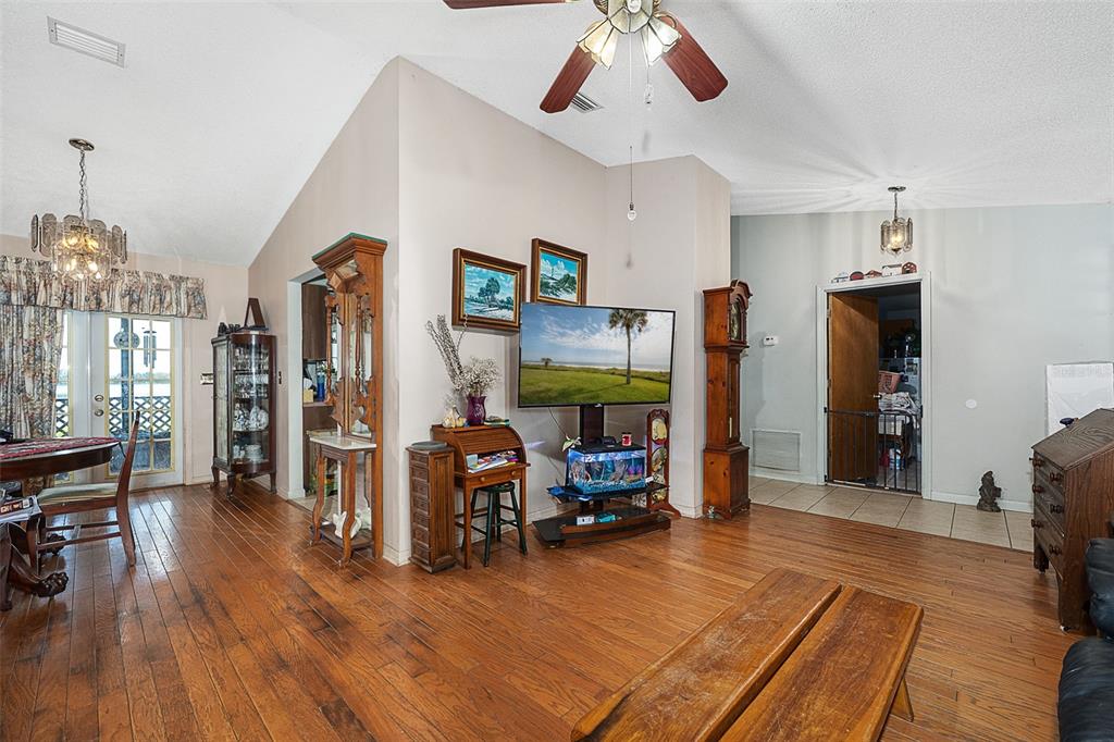 A living room with hardwood floors, a vaulted ceiling, a ceiling fan, and a television — 2372 MITCHELL ISLAND ROAD, DELTONA, FL