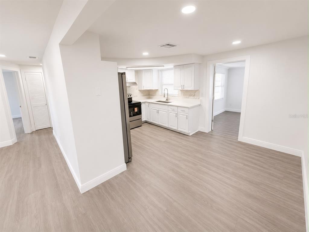 A kitchen with white cabinets, stainless steel appliances, and light wood-look flooring — 4116 OAKFIELD AVENUE, HOLIDAY, FL