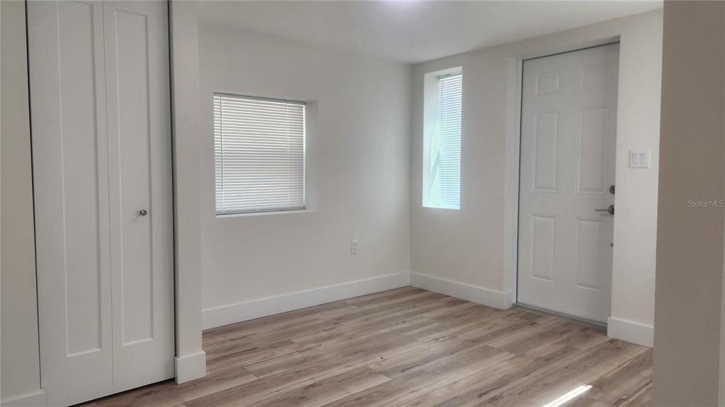 A room with light-colored walls, wood-look flooring, two windows with blinds, and a white door — 2117 5TH STREET UNIT Front House, SARASOTA, FL