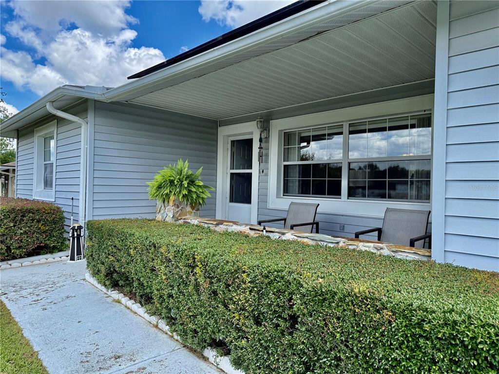 A light blue house features a covered front porch with a stone planter and hedge — 273 W CASURINA PLACE, BEVERLY HILLS, FL