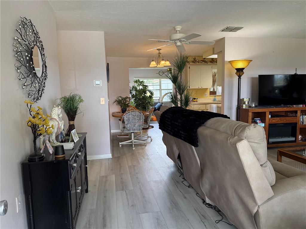 A living room with light wood-look flooring leads to a dining area and kitchen — 273 W CASURINA PLACE, BEVERLY HILLS, FL