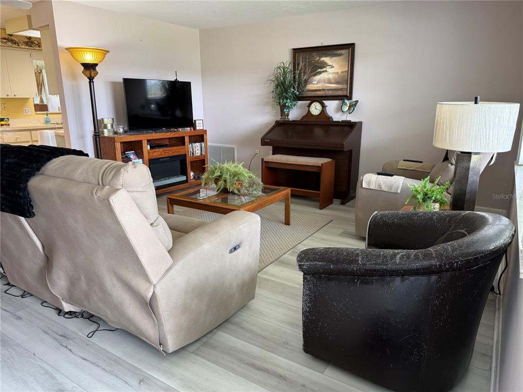 A living room features light wood-look flooring, a television console, a piano, and seating furniture — 273 W CASURINA PLACE, BEVERLY HILLS, FL