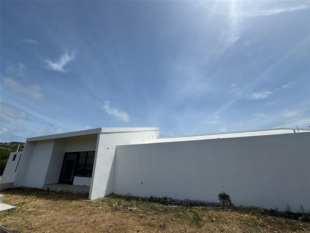A low-slung, white modern house exterior sits under a bright blue sky — 8 ALTURAS DE ZONI, CULEBRA, PR