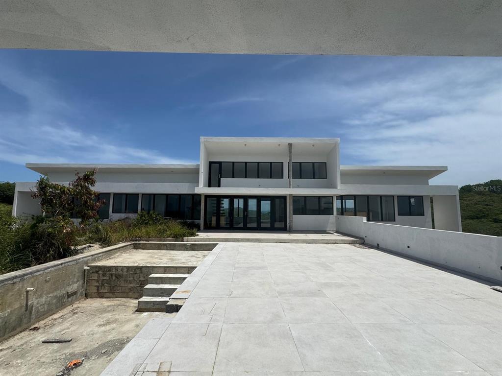 A modern white house with large windows and a spacious tiled patio under a blue sky — 8 ALTURAS DE ZONI, CULEBRA, PR