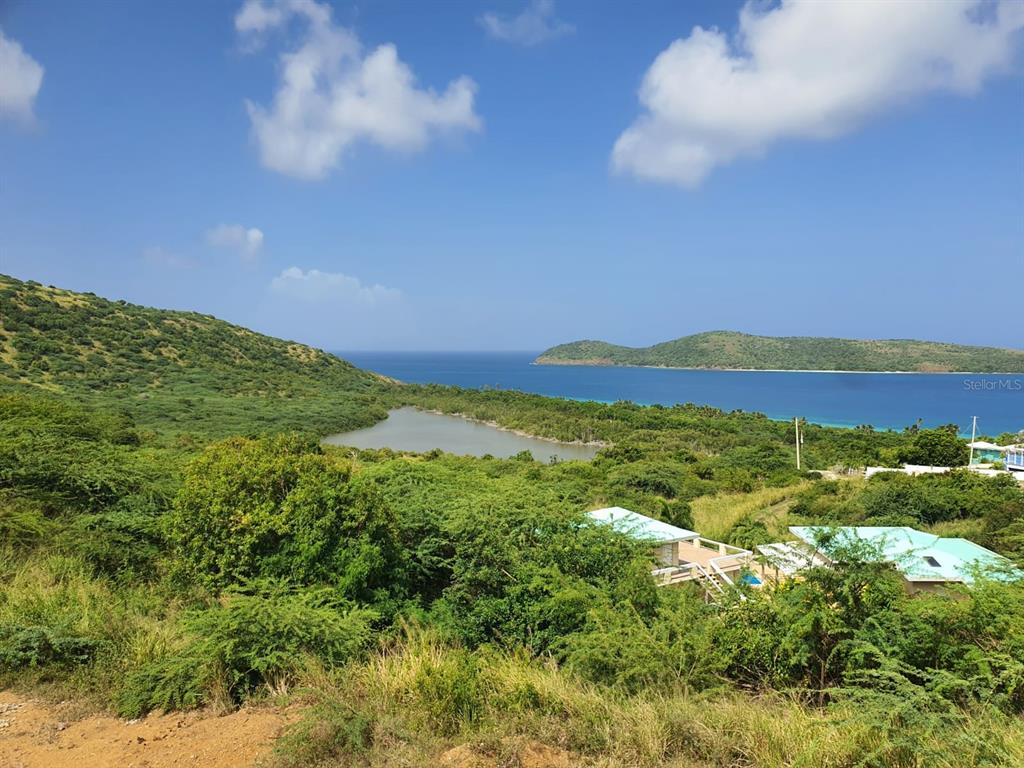 An elevated view of a coastal landscape featuring a small pond, hills, and ocean water — 8 ALTURAS DE ZONI, CULEBRA, PR