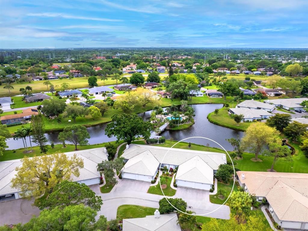 An aerial view shows a residential villa with a white roof near a community pond — 3130 RINGWOOD MEADOW UNIT 44, SARASOTA, FL