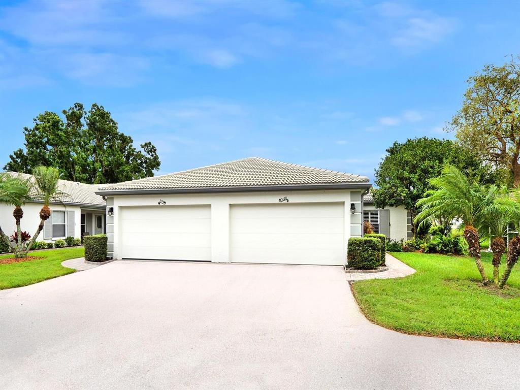 A single-story house features a two-car garage, a tiled roof, and surrounding landscaping — 3130 RINGWOOD MEADOW UNIT 44, SARASOTA, FL