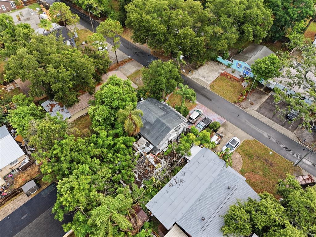An aerial view shows several houses surrounded by trees and a paved street with cars — 1734 CRAWFORD AVENUE, CLEARWATER, FL