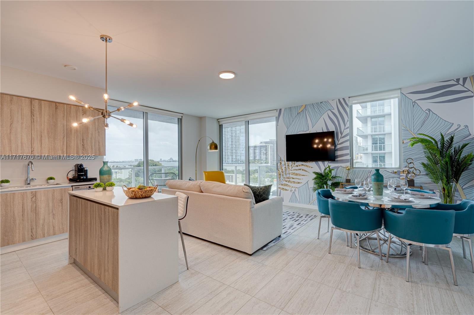 An open-concept living and dining area features light wood cabinetry, teal chairs, and a balcony — 3900 Biscayne Blvd # 717, Miami FL 33137, MIAMI, FL