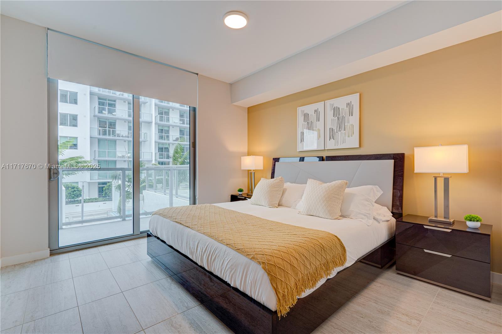 A bedroom features a platform bed, two nightstands with lamps, and a sliding glass door — 3900 Biscayne Blvd # 717, Miami FL 33137, MIAMI, FL