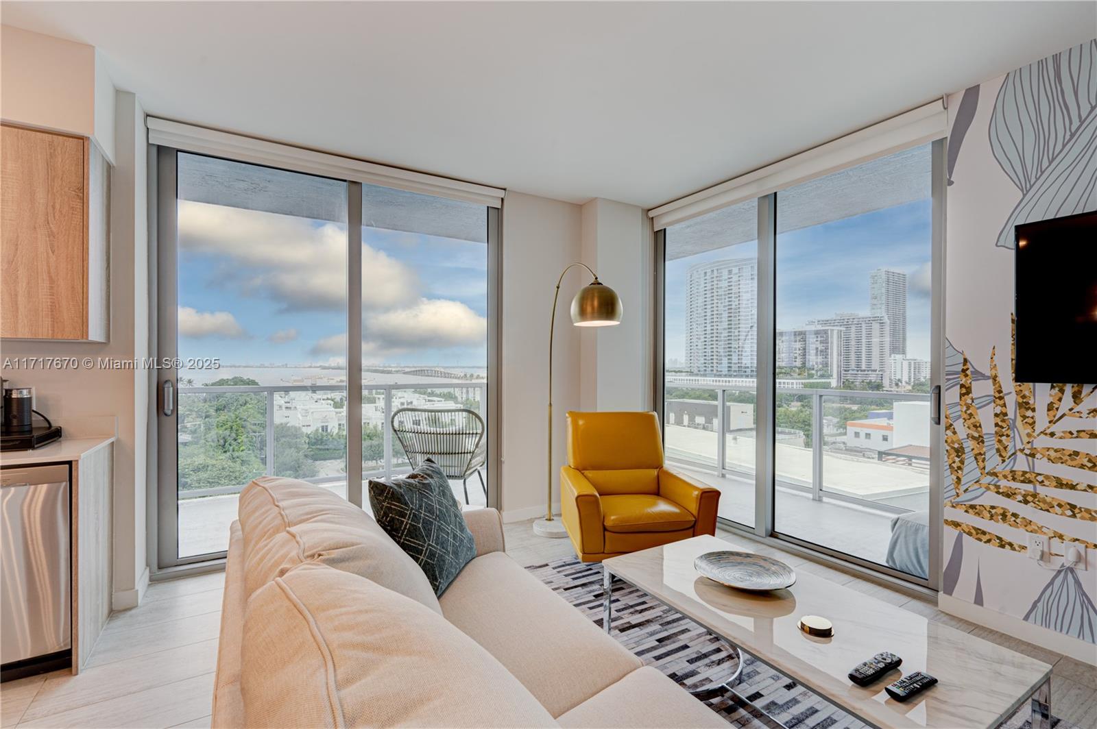 A living room features a beige sofa, yellow armchair, coffee table, and floor-to-ceiling windows — 3900 Biscayne Blvd # 717, Miami FL 33137, MIAMI, FL