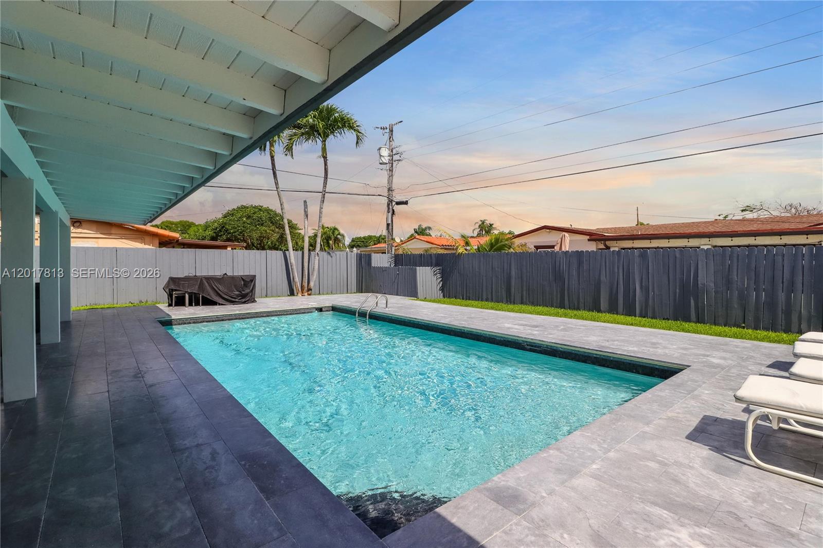 A rectangular swimming pool sits on a tiled patio next to a covered porch area — 12535 SW 31st Ter, Miami FL 33175, MIAMI, FL