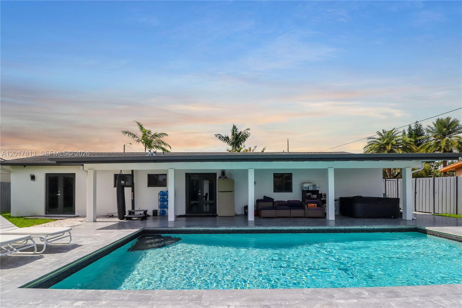 A backyard features a swimming pool, a covered patio with lounge furniture, and palm trees — 12535 SW 31st Ter, Miami FL 33175, MIAMI, FL