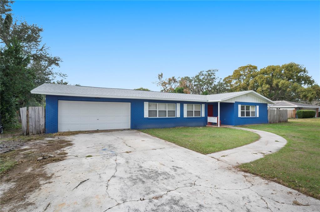 A single-story blue brick house with a white garage door and a concrete driveway — 4911 WHITEOAK DRIVE E, LAKELAND, FL