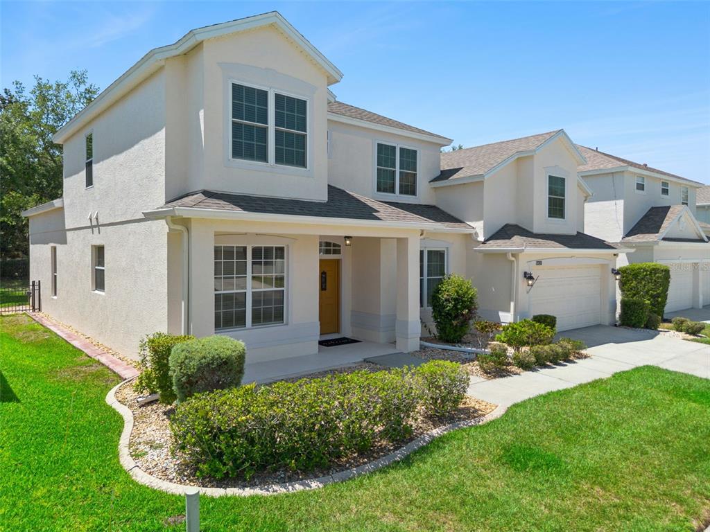 A two-story suburban house with a tan stucco exterior, a front porch, and a garage — 10125 SANDY MARSH LANE, ORLANDO, FL