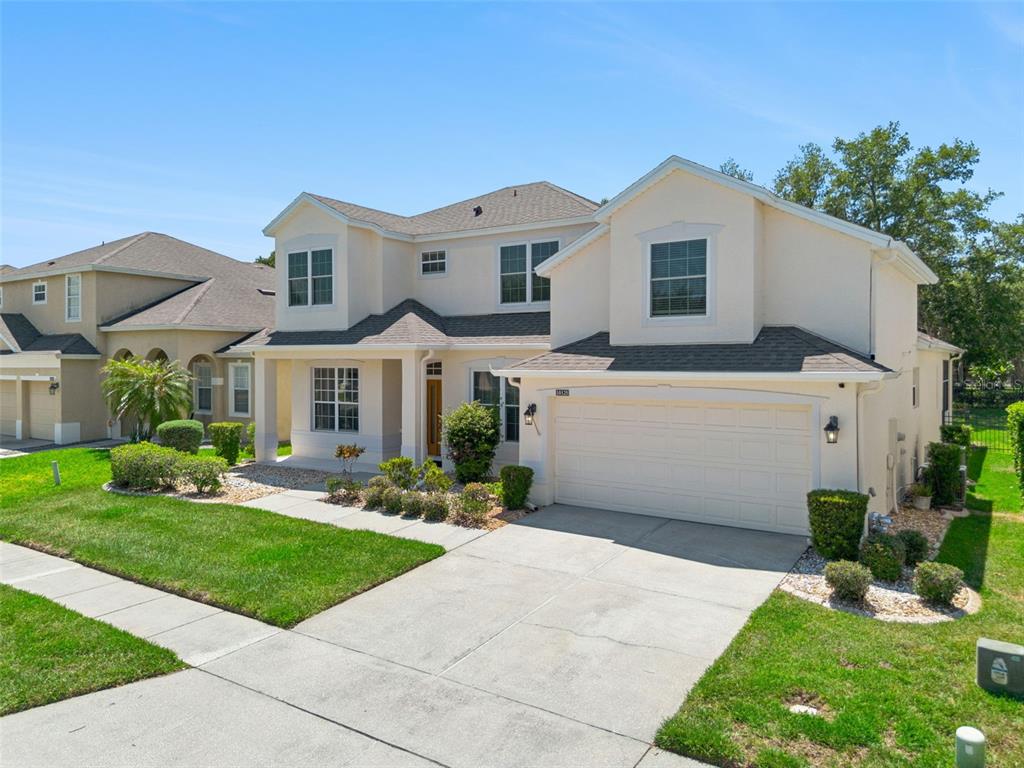 A two-story suburban house with a beige stucco exterior, a two-car garage, and green landscaping — 10125 SANDY MARSH LANE, ORLANDO, FL